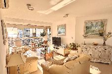 Living amplio con sillones, TV y grandes ventanales