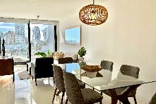 Comedor y sala modernos con mesa de vidrio y vista a la ciudad