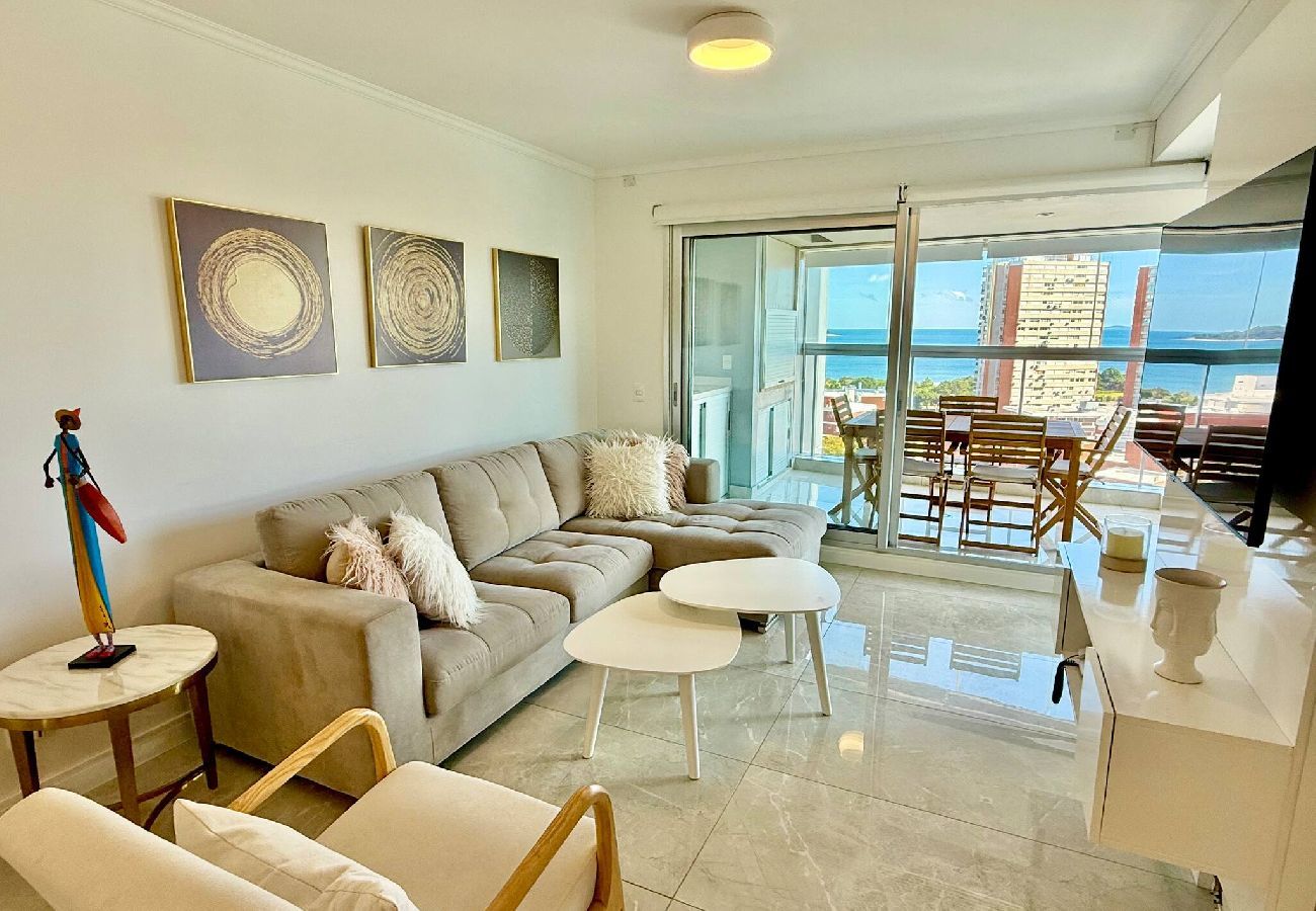 Salón amplio con sofá seccional y acceso a balcón con vista al mar