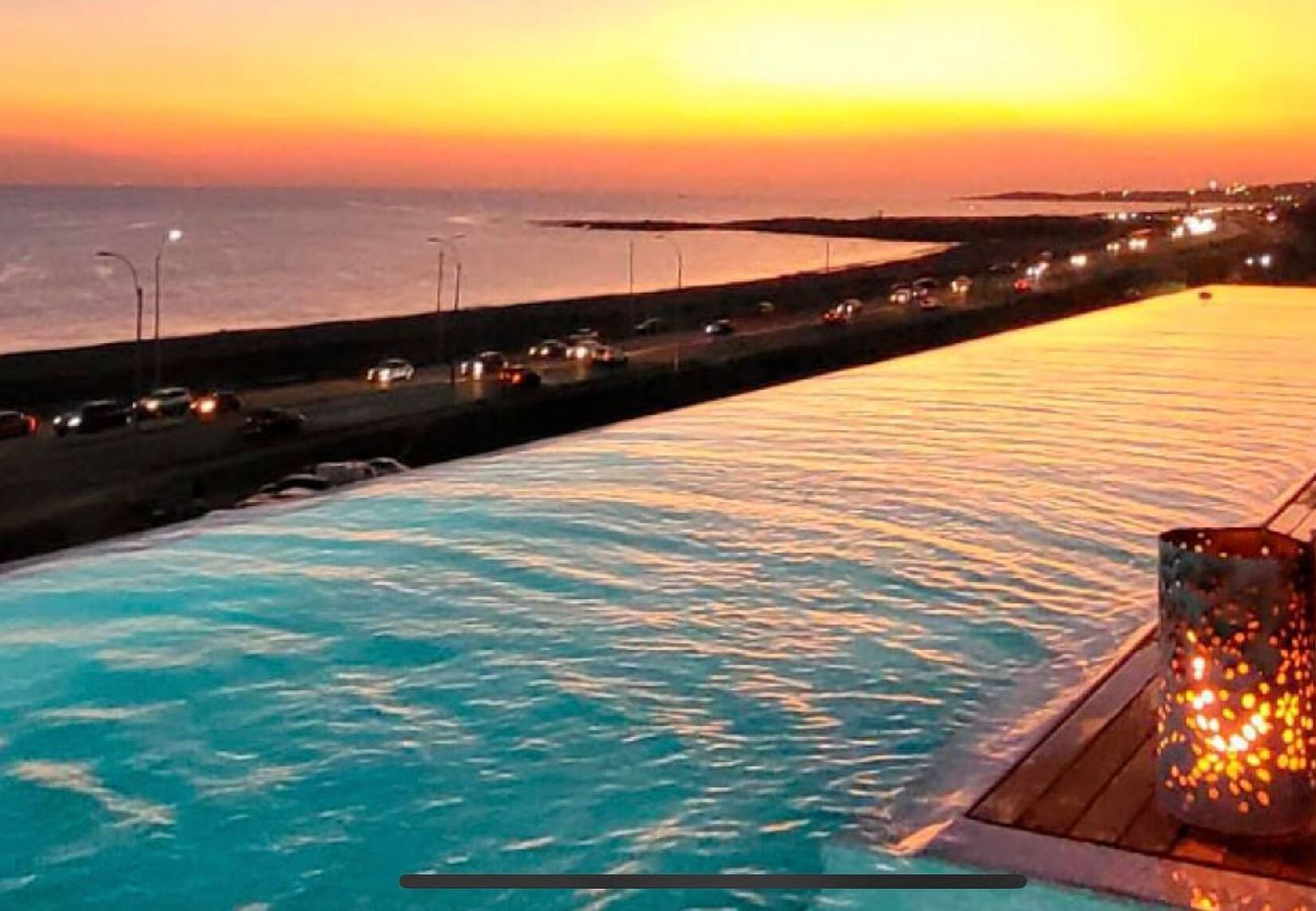 Piscina climatizada grande con deck de madera y vista al mar