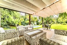 Living exterior techado con césped y vista a la piscina