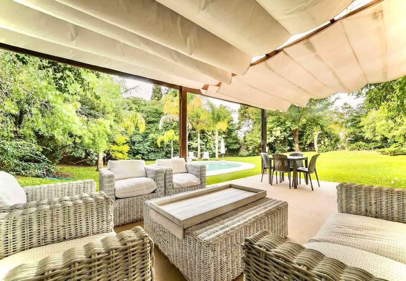 Living exterior techado con césped y vista a la piscina